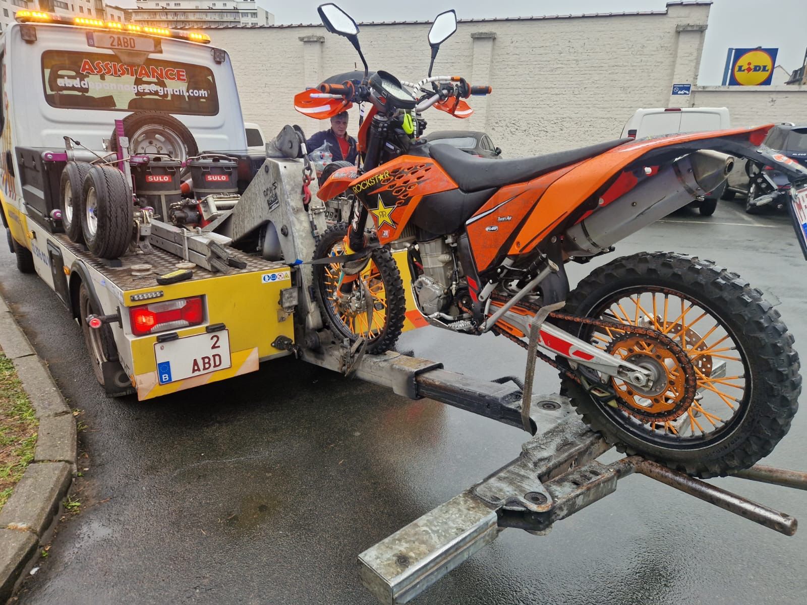 Remorquage moto KTM enduro orange sur plateau ABD Depannage a Bruxelles — sangles et berceau adaptes